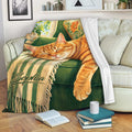 Tabby cat throw blanket draped across a sofa, showing a cozy reading nook with books