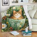 Tabby cat blanket displayed on a sofa with leafy floral artwork and a cozy reading nook