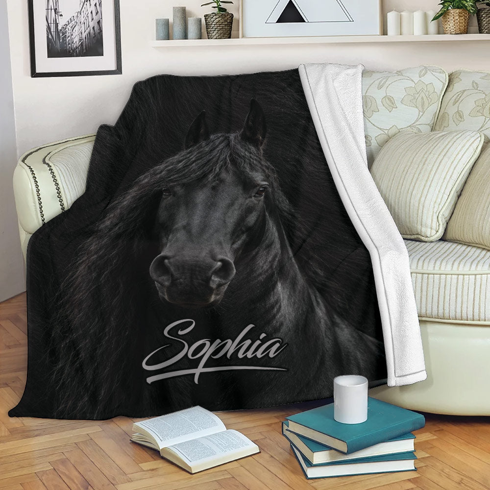 Black horse throw blanket styled over a living room sofa with books and a warm reading nook