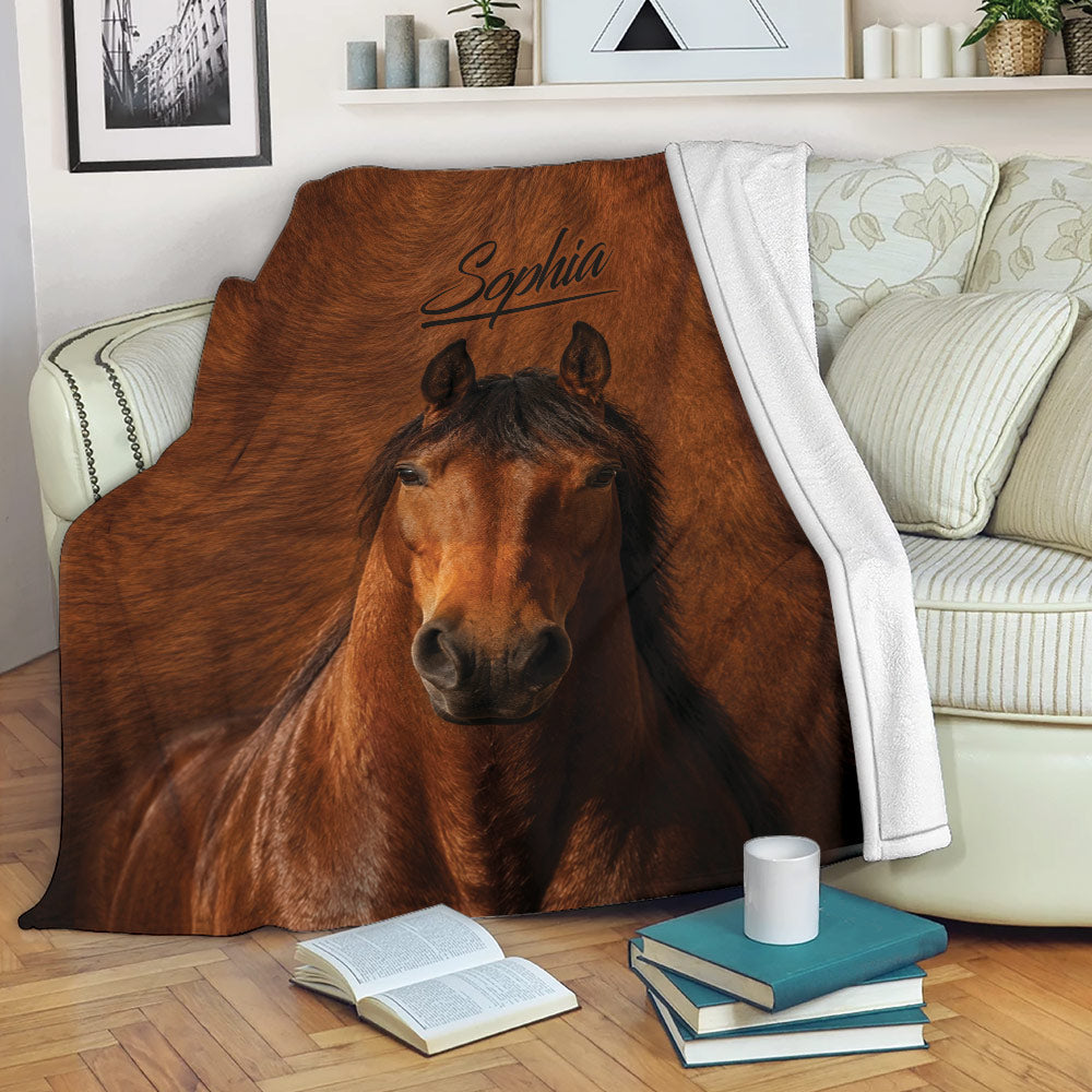 Brown horse throw blanket styled on a sofa with books and a mug in a cozy living room
