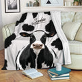 Black and white cow blanket draped over a sofa in a cozy living room setting