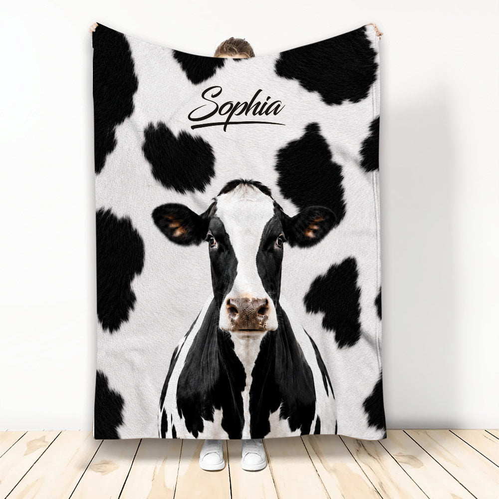 Black and white cow throw blanket displayed with a large cow face and spotted farm animal design
