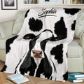 Cow throw blanket spread across a sofa with bold black-and-white farm animal artwork
