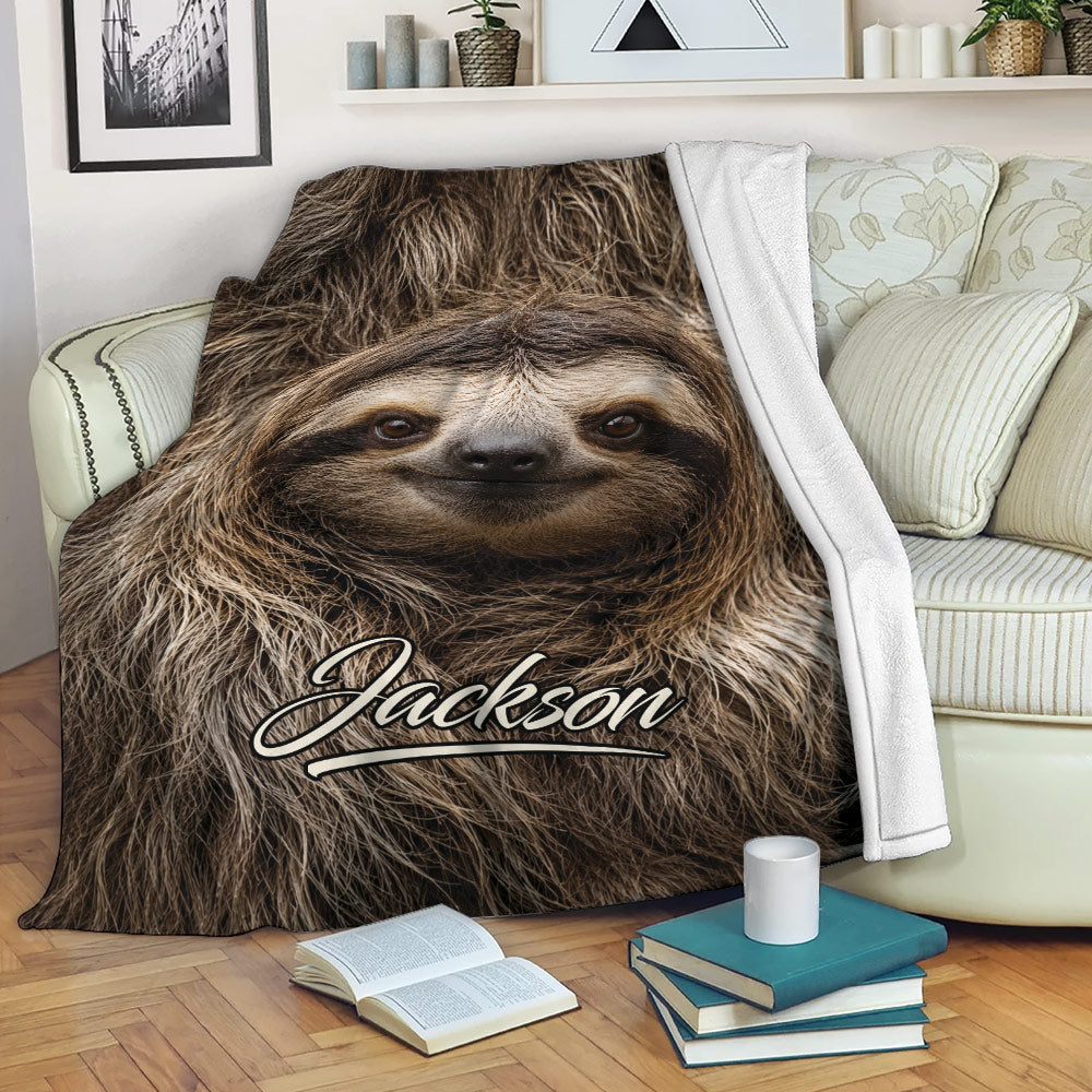 Sloth throw blanket draped over a sofa with cozy living room decor and sloth artwork