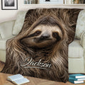 Close-up sloth throw blanket displayed across a sofa with detailed woodland-inspired artwork