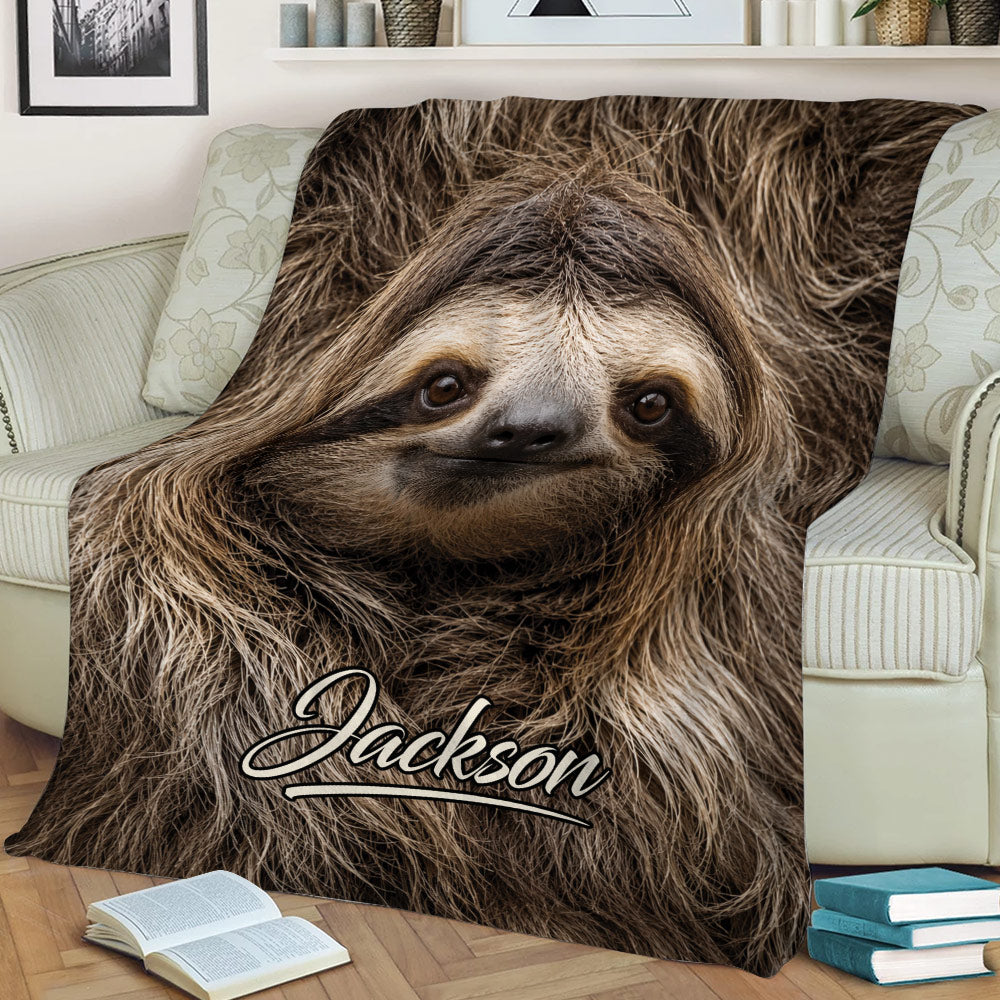 Close-up sloth throw blanket displayed across a sofa with detailed woodland-inspired artwork