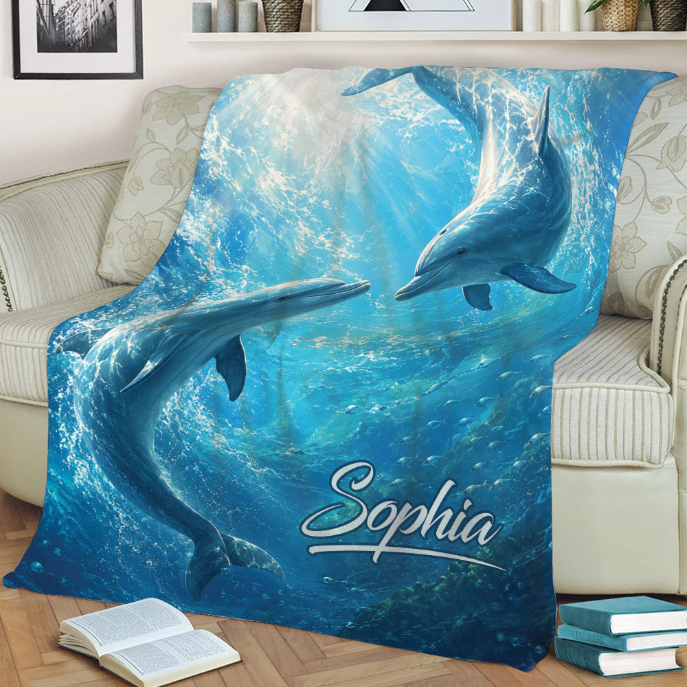 Blue dolphin blanket displayed across a sofa with two dolphins and underwater sea life