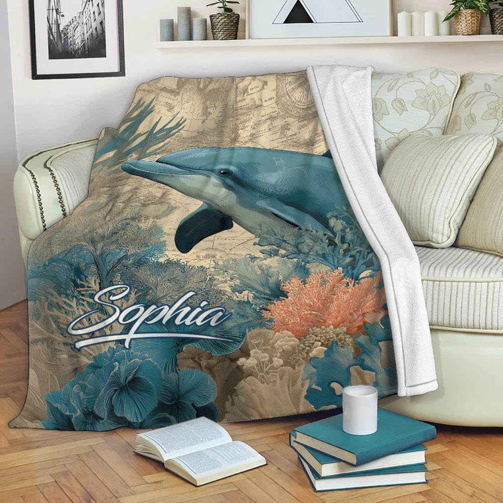 Dolphin throw blanket draped over a sofa with nautical map, coral reef and ocean artwork
