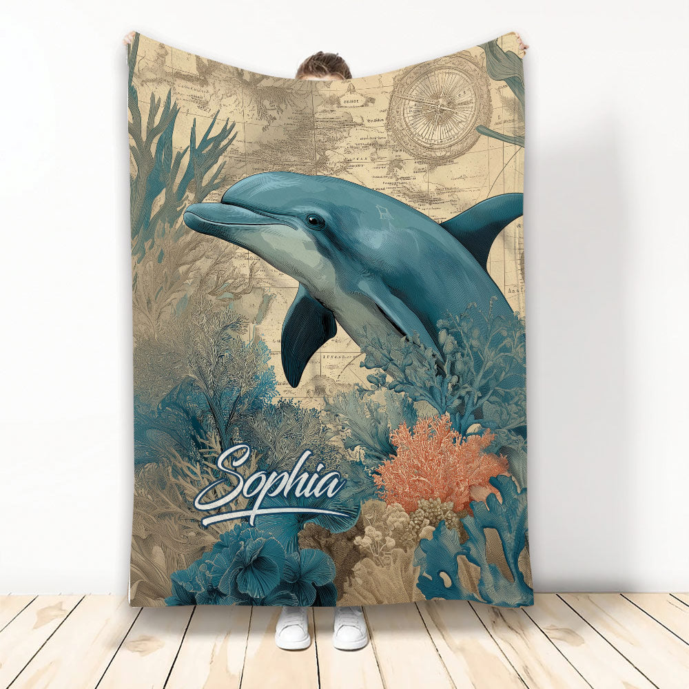 Dolphin throw blanket displayed against a wall with vintage map and colorful underwater coral artwork