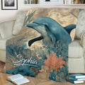 Dolphin blanket styled on a sofa, featuring vintage map details, sea plants and coral reef artwork