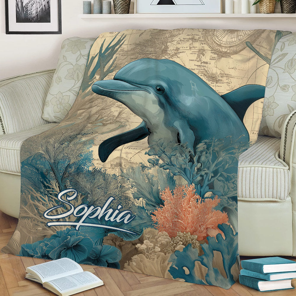 Dolphin blanket styled on a sofa, featuring vintage map details, sea plants and coral reef artwork