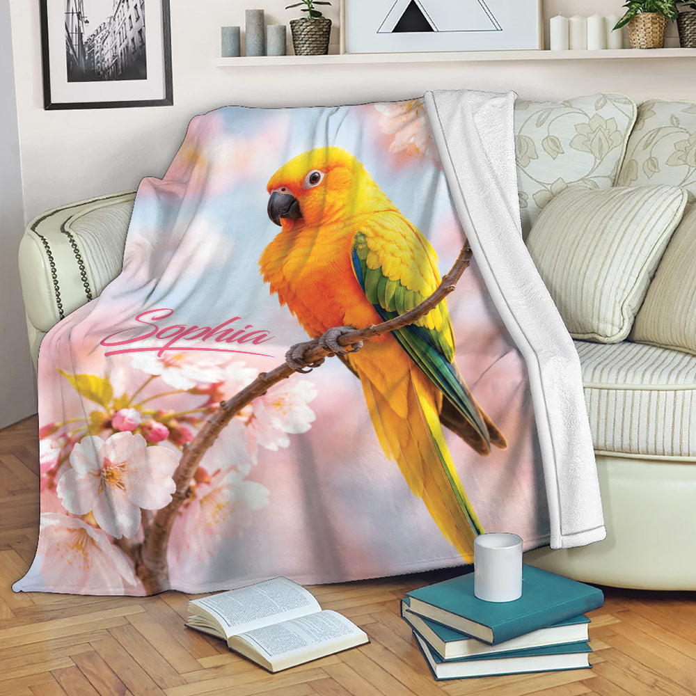 Conure bird throw blanket with colorful feathers and cherry blossom artwork draped over a sofa