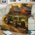 Rustic tractor blanket styled on a sofa, featuring a vintage green tractor, farmhouse, and golden fall landscape