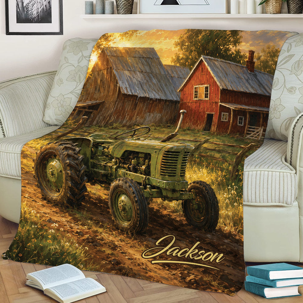 Rustic tractor blanket styled on a sofa, featuring a vintage green tractor, farmhouse, and golden fall landscape