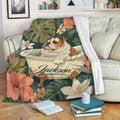 English Bulldog throw blanket displayed on a sofa with tropical flowers, botanical leaves, and a cozy reading setting