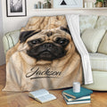 Pug throw blanket displayed on a sofa with a close-up dog design in warm neutral tones
