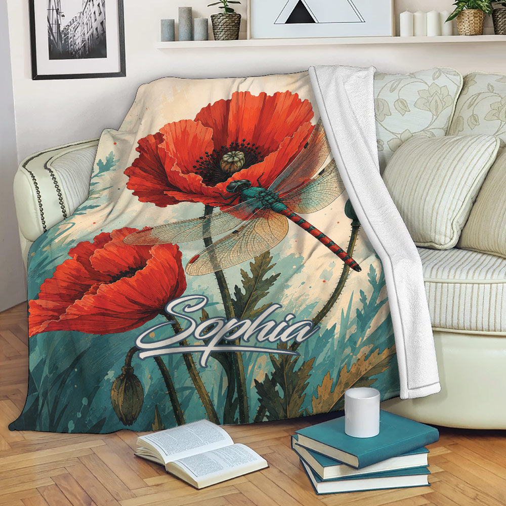 Dragonfly throw blanket with red poppy artwork styled on a sofa with books