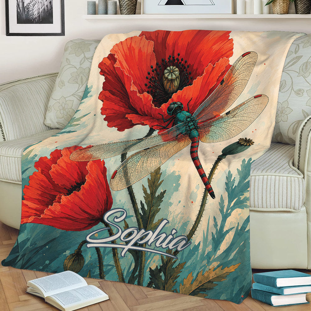 Close view of dragonfly and red poppy artwork on a botanical throw blanket