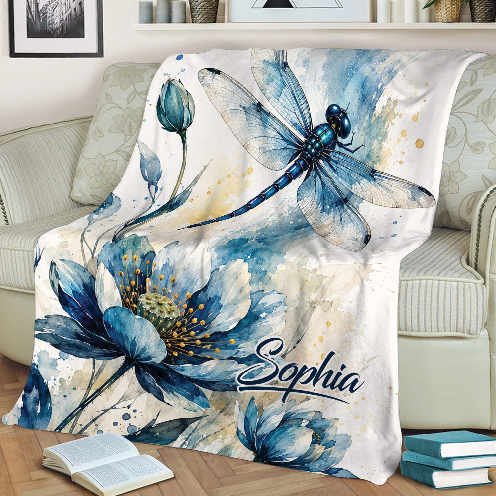 Close view of a dragonfly and blue flower watercolor blanket draped over a sofa