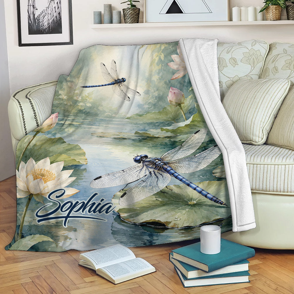 Dragonfly throw blanket displayed on a sofa with lotus pond artwork and tranquil nature colors