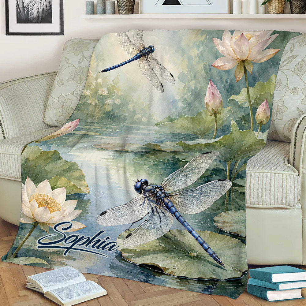 Dragonfly blanket draped over a chair, featuring lotus flowers, lily pads, and watercolor scenery