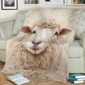 Close-up sheep throw blanket displayed on a sofa with soft cream-colored farm animal artwork