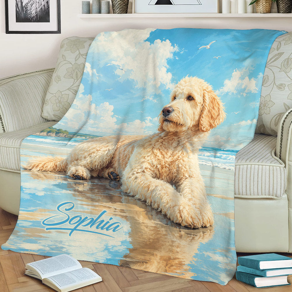 Beach-themed Goldendoodle blanket draped over a sofa with a curly dog resting by the ocean