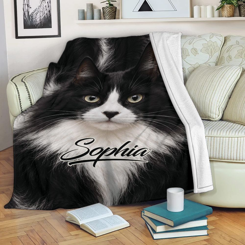 Tuxedo cat throw blanket draped across a sofa in a cozy living room setting
