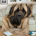 Close-up English Mastiff throw blanket displayed on a sofa with warm neutral dog artwork