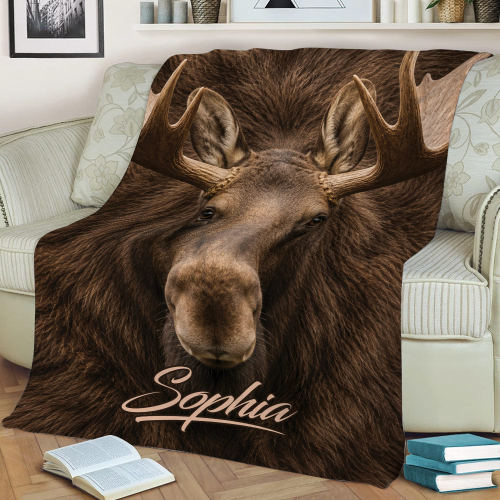 Close-up moose artwork covering a throw blanket styled across a living room sofa