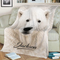 Close-up polar bear throw blanket displayed on a sofa with arctic wildlife artwork
