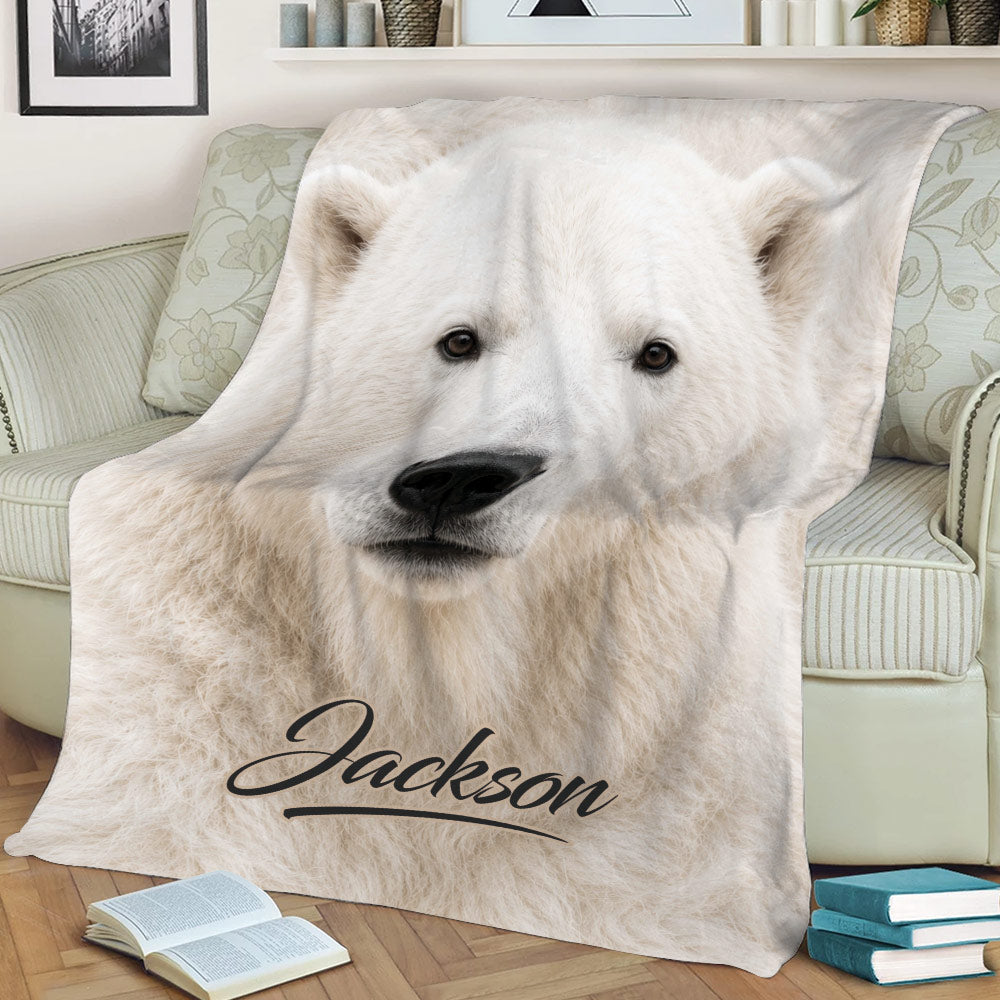 Close-up polar bear throw blanket displayed on a sofa with arctic wildlife artwork