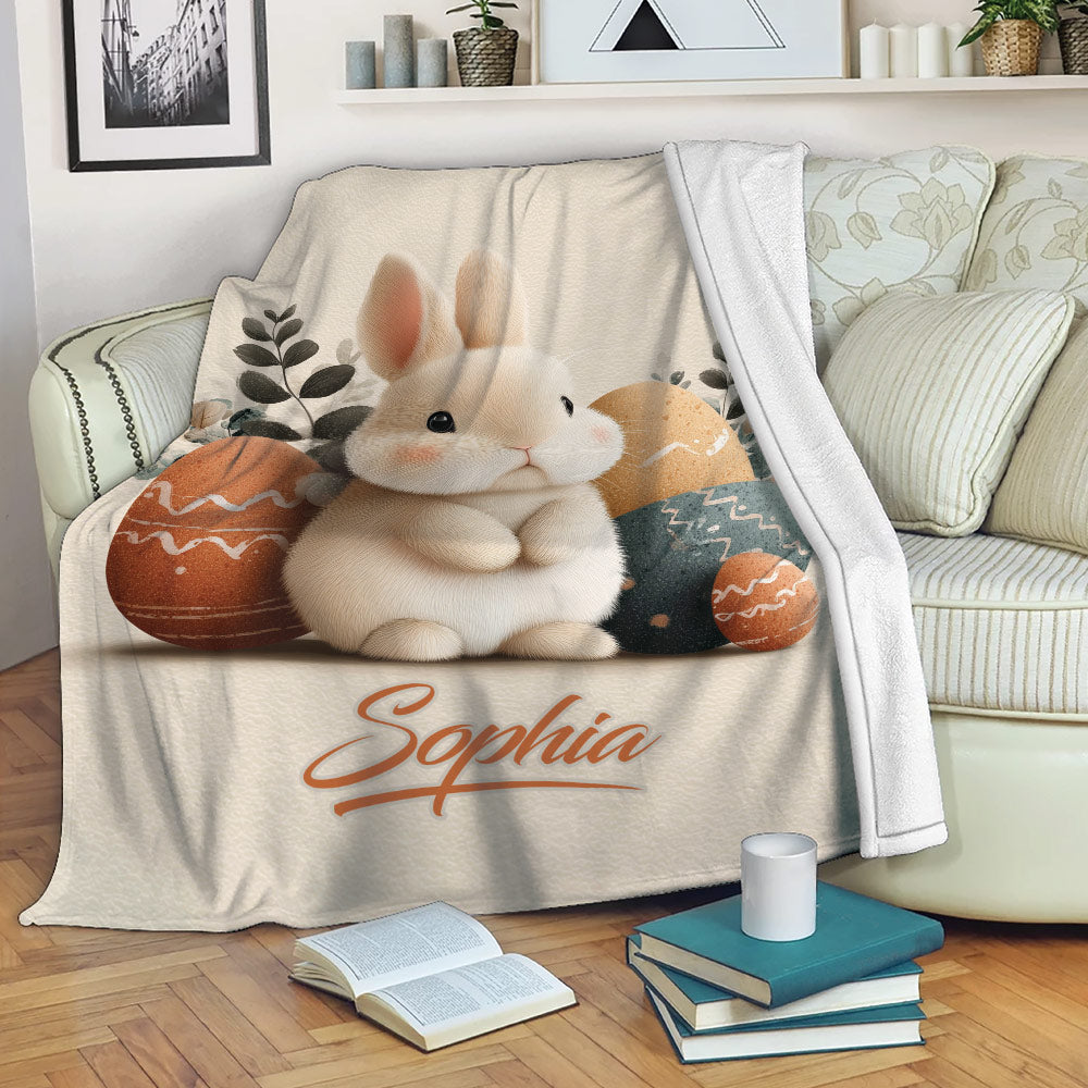 Rabbit throw blanket displayed on a sofa with a bunny and decorative Easter egg artwork