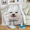Bichon Frise dog blanket draped over a sofa with books and a cup nearby