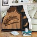 Taco throw blanket draped over a sofa, featuring illustrated tacos, sombrero artwork, and chili pepper accents