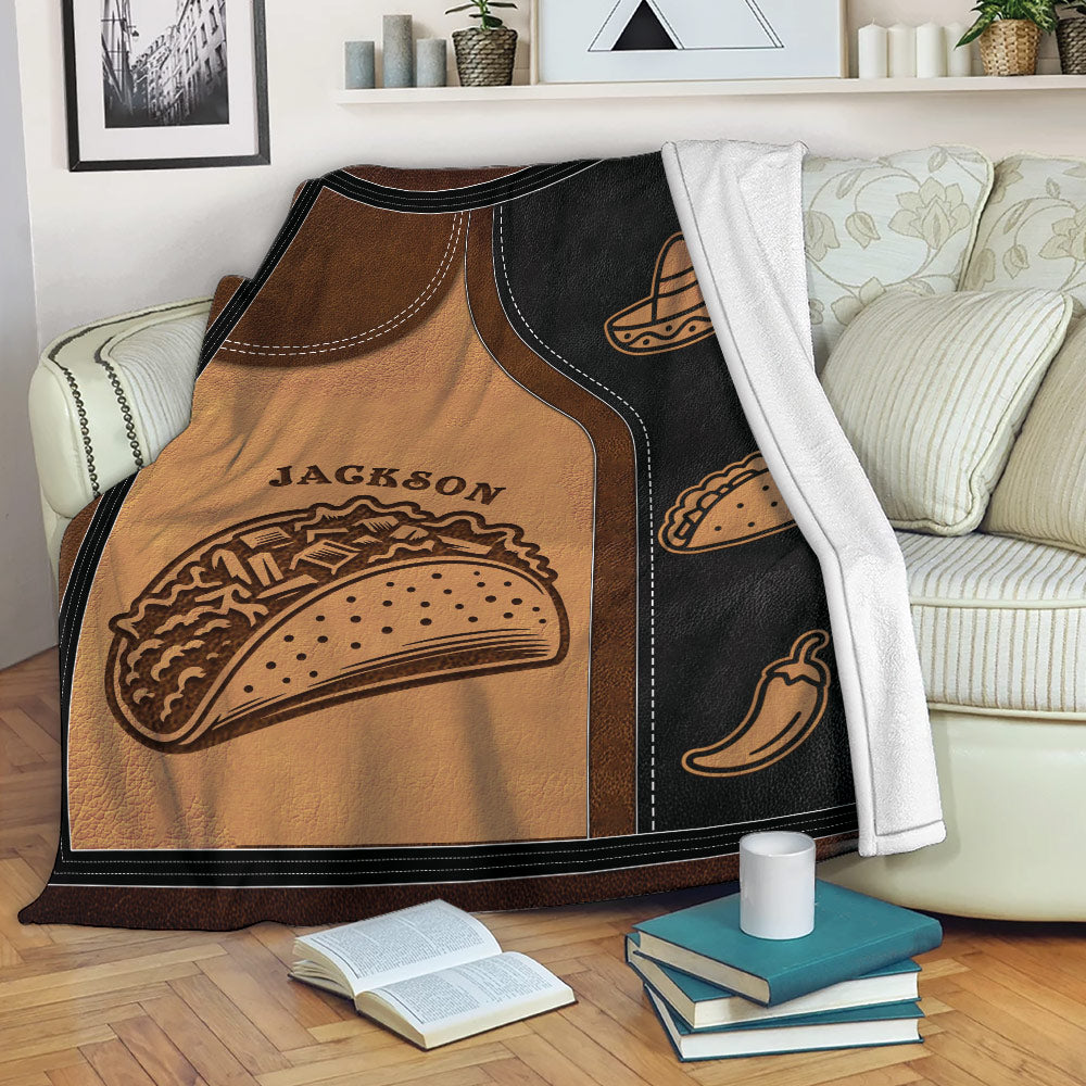 Taco throw blanket draped over a sofa, featuring illustrated tacos, sombrero artwork, and chili pepper accents