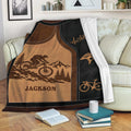 Bicycle throw blanket displayed on a sofa with mountain biking artwork and warm brown and black tones