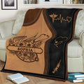 Close view of a caregiver throw blanket featuring medical symbols, floral accents, and warm brown artwork