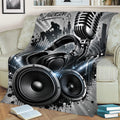 Music-themed DJ blanket draped across a sofa with large speakers, headphones, microphone, and equalizer design