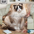 Floral Ragdoll cat throw blanket draped over a sofa with a fluffy blue-eyed cat