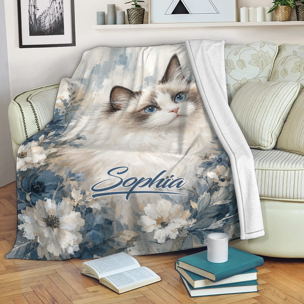 Ragdoll cat blanket draped over a sofa with blue floral artwork in a cozy living room