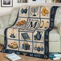 Hanukkah blanket draped over a sofa with menorah, Torah scroll, dreidels, gelt, and blue and gold artwork