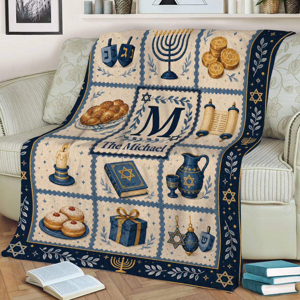 Hanukkah blanket draped over a sofa with menorah, Torah scroll, dreidels, gelt, and blue and gold artwork