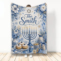 Blue and gold Hanukkah throw blanket with floral menorah artwork, dreidels, candles, gifts, and pastries