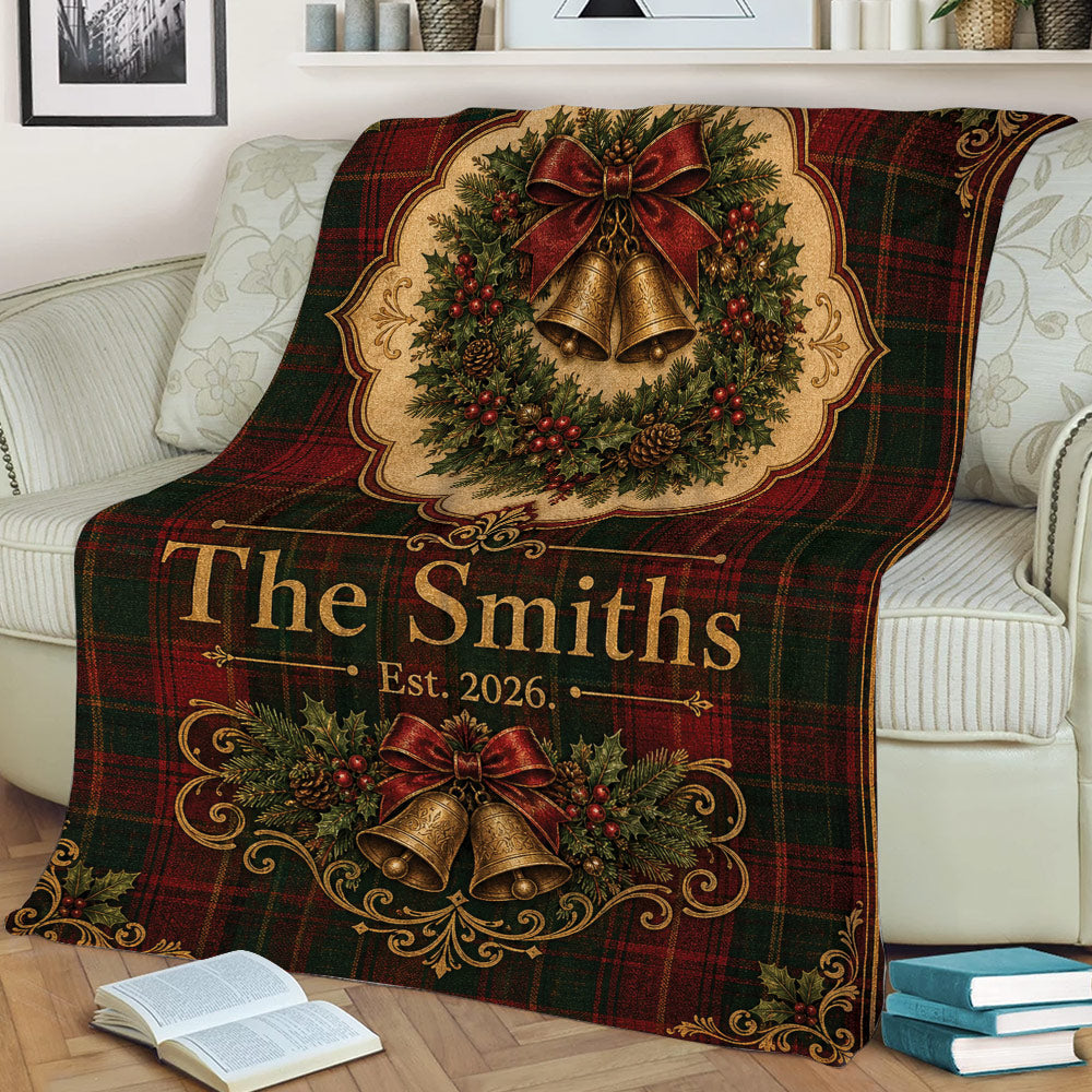 Festive Christmas throw blanket displayed on a sofa with red tartan, holly, bows, and golden bells