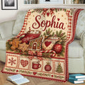 Cozy holiday throw blanket draped over a sofa with vintage Christmas cocoa and gingerbread artwork
