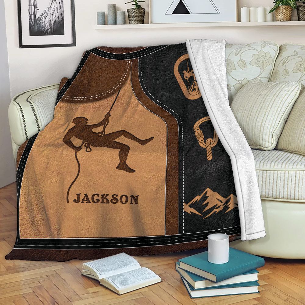 Rock climbing throw blanket draped over a sofa with climber, rope, carabiner, and mountain design