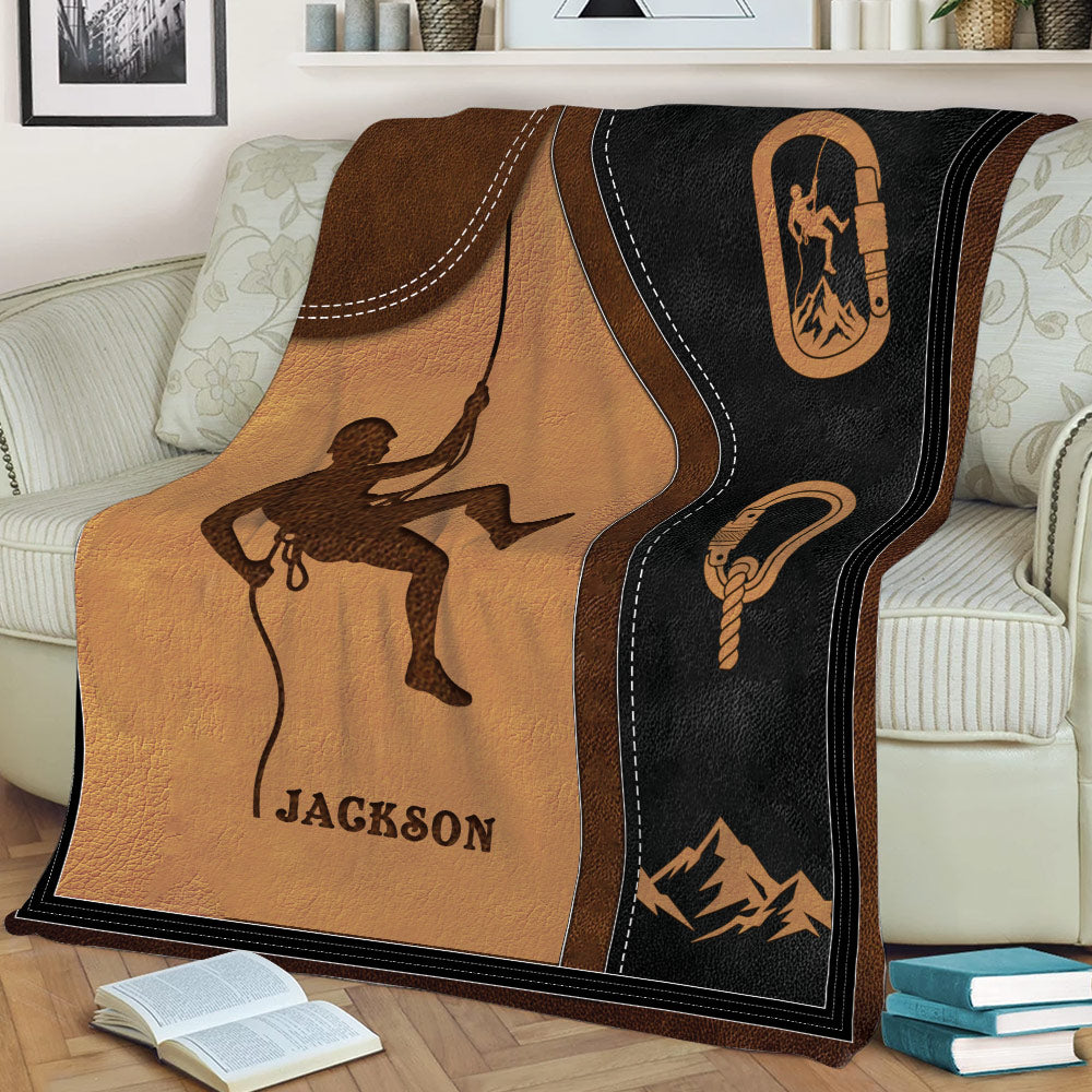 Close view of rock climbing blanket featuring a climber silhouette, climbing gear, and mountain artwork