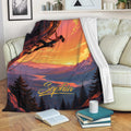 Rock climbing throw blanket displayed on a sofa with a sunset mountain scene and climber artwork