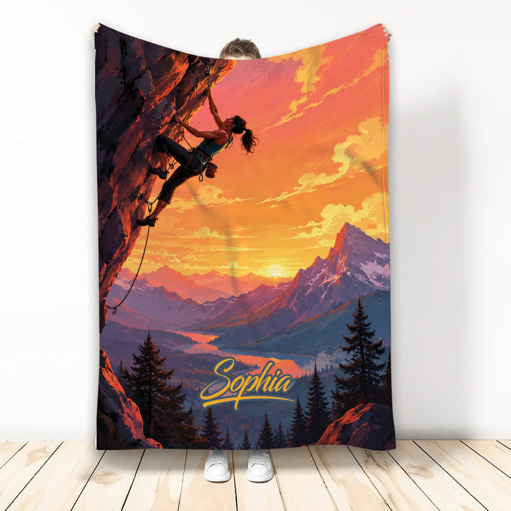 Rock climbing blanket featuring a climber on a cliff above a vibrant sunset mountain landscape